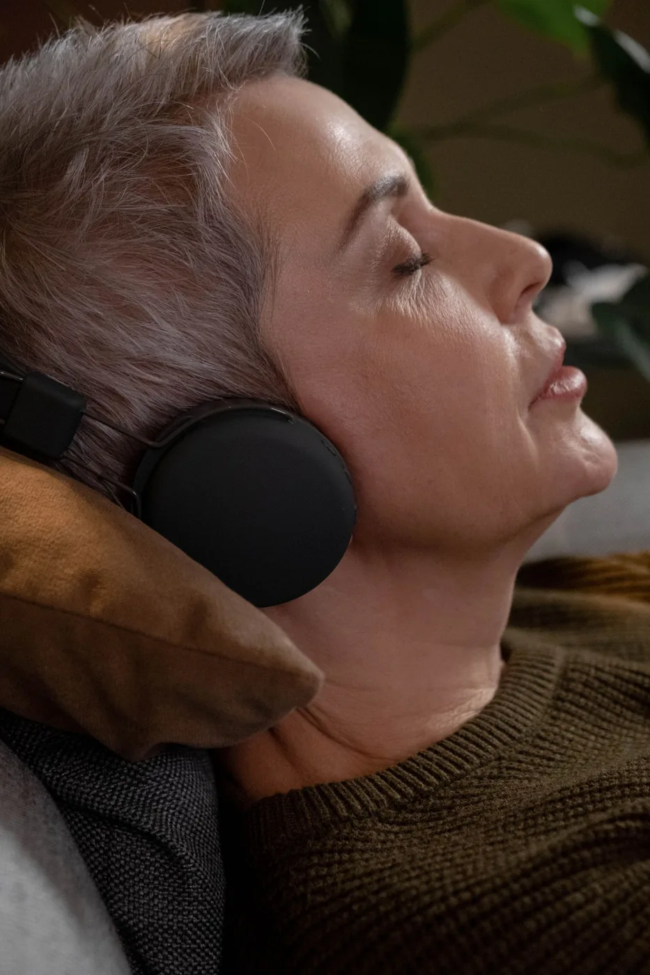 Woman listening to over-ear headphones with her eyes closed at home