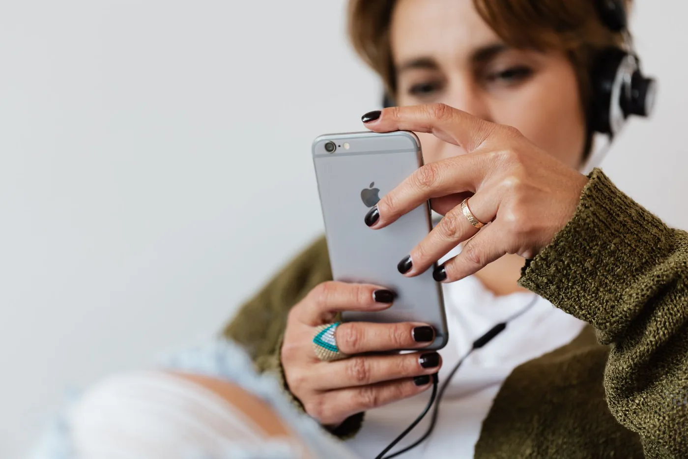 Woman wearing over-ear headphones while using a smartphone indoors