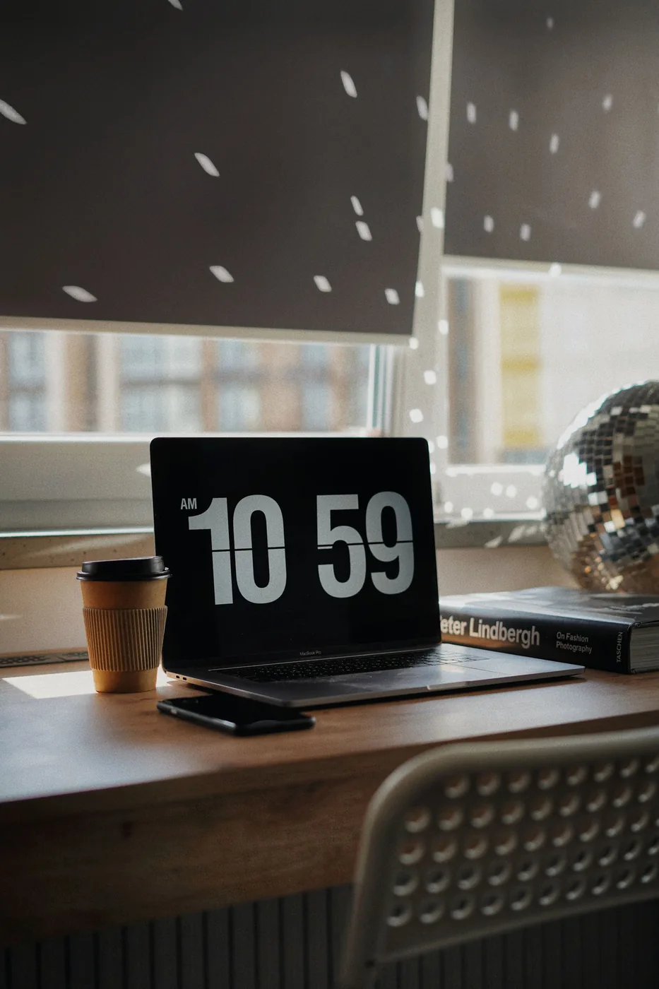 Laptop and a cup of coffee on a wooden home office desk beside a window