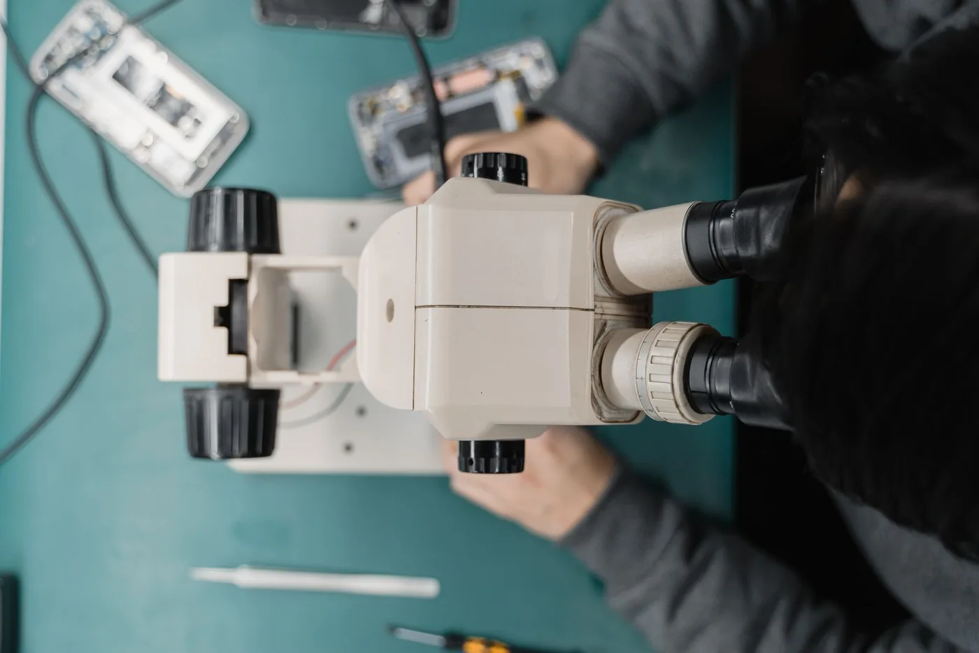 Technician working on a smartphone with a microscope at a repair bench