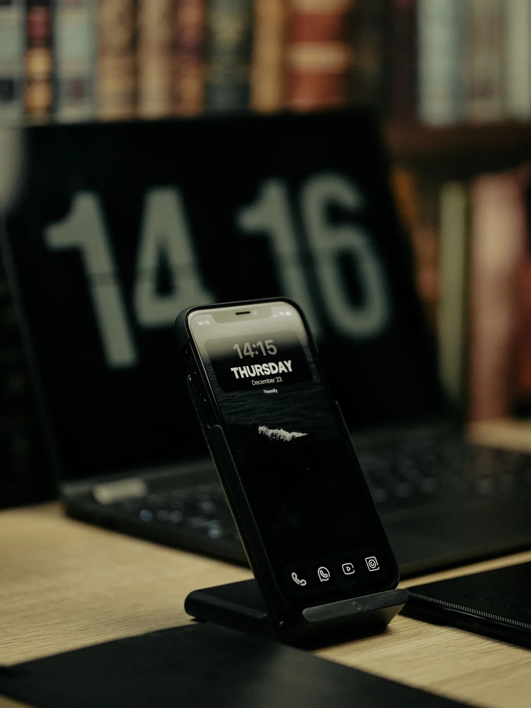 Smartphone resting on a wireless charging stand in front of a laptop