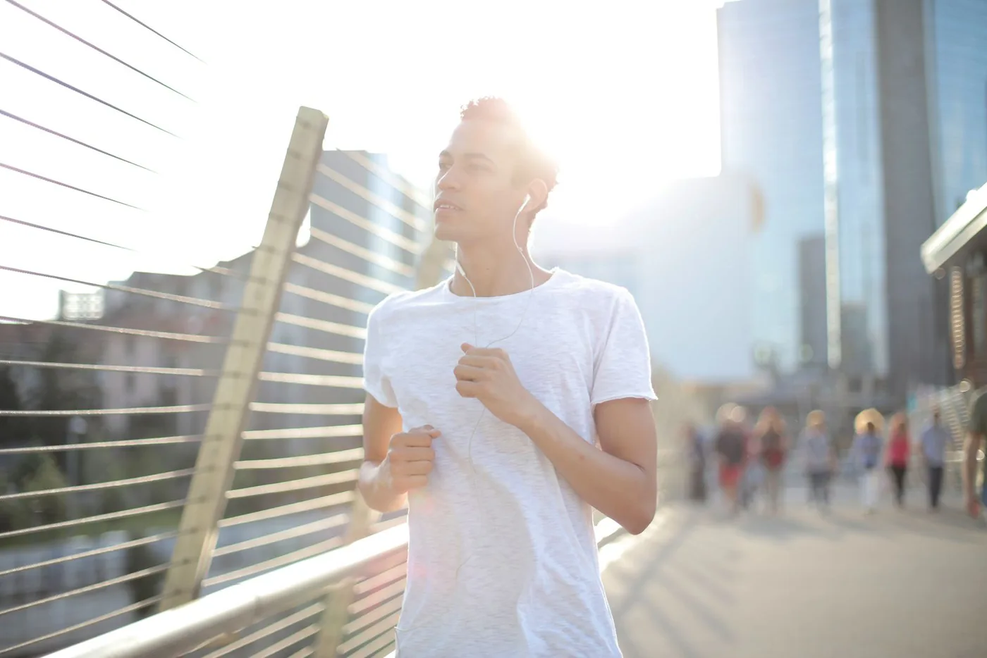 Runner wearing earbuds on a city street in late afternoon light